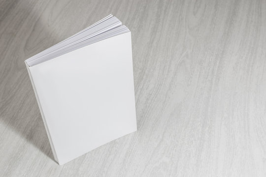 Real 3D paperback white books on a wood background