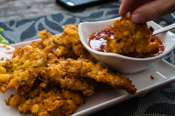 Indonesian dish jagung goreng in close up with hand dipping in sauce