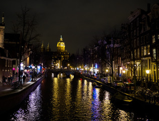 Night illumination of buildings near the water in the canal in Amsterdam
