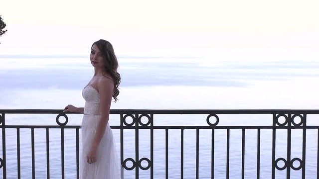 the bride standing on a balcony on the sea background.