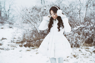 Young beautiful happy girl walking in park. Model wearing stylish winter clothing. Outdoor active fun.