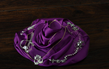 Jewelry on the violet satin rose. Selective focus and small depth of field.