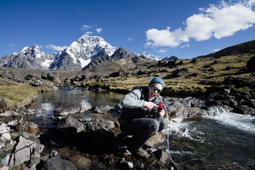 Junger Abenteurer filtert Wasser aus einem Gebirgsfluss am Fuss des Ausangate 6384m, Kordillere...