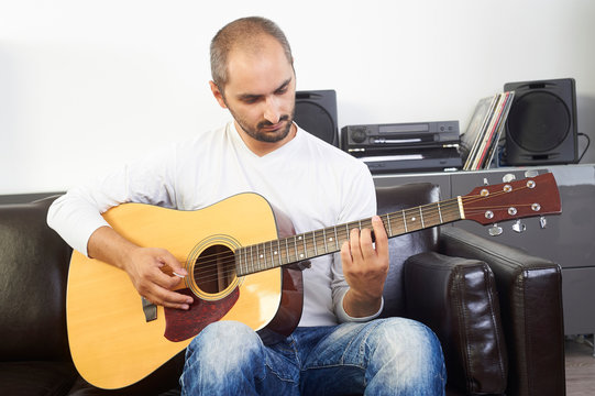 adult man play acoustic guitar at home living