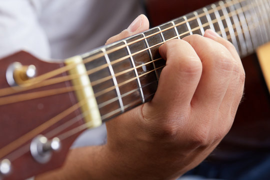 Close up of guitarist hand playing acoustic guitar