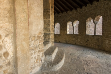 Stone aisle of a castle with arched windows in the background