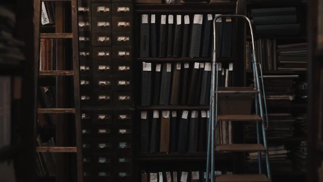Dolly shot interior of an old library bookshelves with document folders