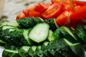 sliced tomatoes and cucumbers lie on a plate, close-up