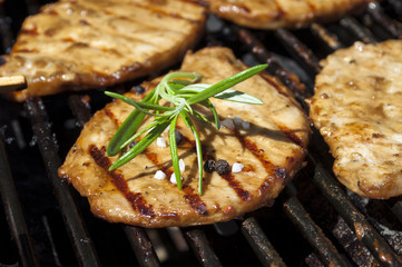 Die Grillsaison ist eröffnet, Grillfleisch auf Grill mit Rosmarin und Flamme