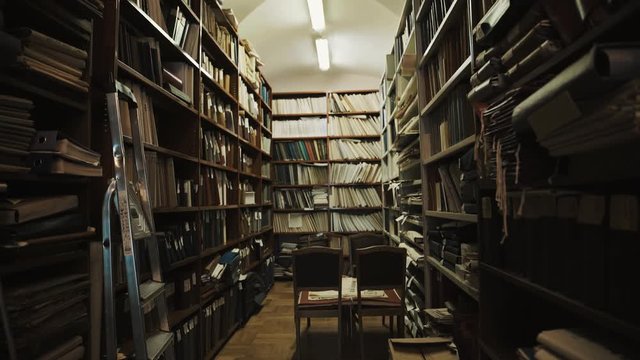 Fluorescent bulbs lights up in an old style library interior. Books and folders