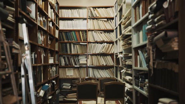 Lights turns on in an old style library interior. Stepladder, books and folders