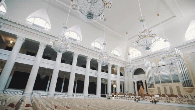 Tracking shot interior empty large old classic style organ hall. Big glass chandeliers