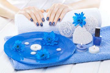 Obraz na płótnie Canvas beautiful blue manicure with chrysanthemum and towel on the white wooden table. spa