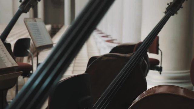 Close up dolly shot of cellos on scene in an empty classical style concert hall