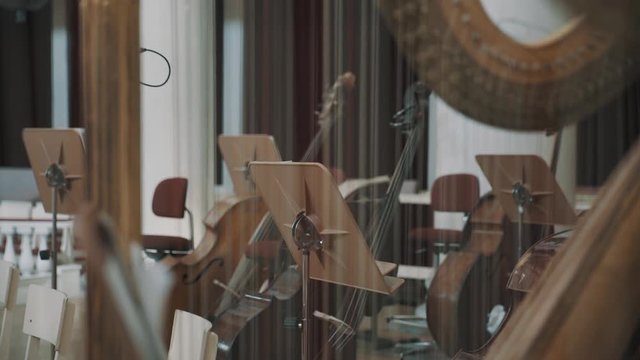 Close up of harp string, music stands and cello on background focus pull