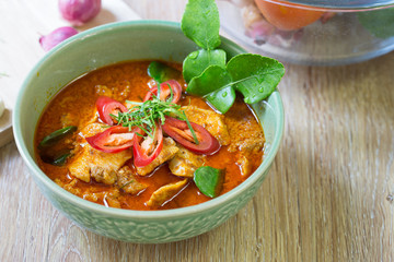 Chicken panang curry in green bowl and ingredient on wooden back