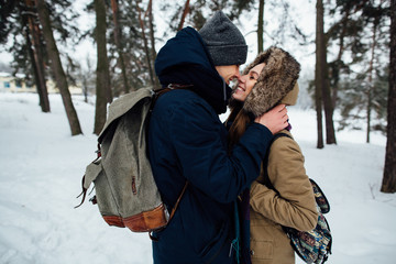 Fototapeta na wymiar Beautiful happy couple in love in winter warm clothes kissing in snowy forest