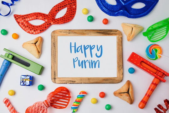 Jewish holiday Purim concept with hamantaschen cookies, carnival mask and photo frame on white background. View from above