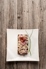 Mushroom salad and ham sandwich with whole grain rye bread on white plate and rustic wood background.