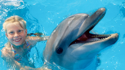 Obraz premium Happy child and dolphins in blue water. Dolphin Assisted Therapy