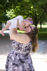 Mom holding up and kissing her daughter