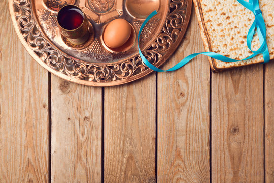 Jewish holiday Passover concept with matzah, seder plate, egg and wine on wooden background. View from above