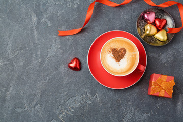 Valentines day concept with coffee cup, chocolate and gift box over dark background. View from above