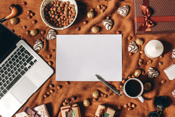 Romantic style background with empty sheet in center, laptop, heart shaped biscuit, pen, coffee cup, gifts, nuts on brown fabric cover. Copyspace, top view, flat lay