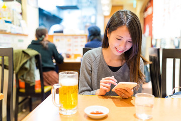 Woman using mobile phone in Japanese ramen shop
