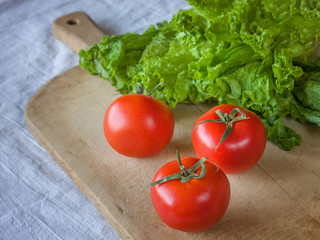 Tomatoes and lettuce on a wooden background.