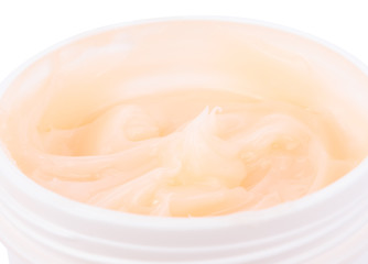 Moisturizing cream in an open jar on white background