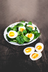 Fresh green spinach baby leaves and boiled eggs cut in a half on