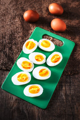 Hard boiled eggs, sliced in halves on cutting board wooden backg