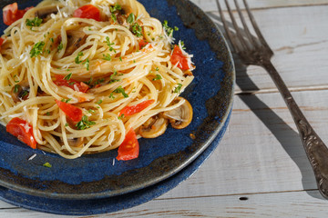vermicelli pasta and tomatoes seasoned with , olives, herbs, mushrooms and Parmesan cheese on an old plate