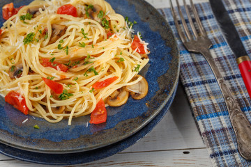 vermicelli pasta and tomatoes seasoned with , olives, herbs, mushrooms and Parmesan cheese on an old plate