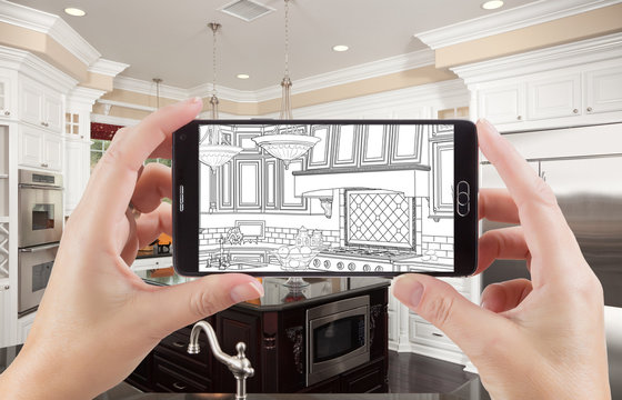Hands Holding Smart Phone Displaying Drawing of Custom Kitchen Photo Behind.