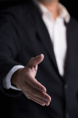 Fototapeta premium A business man wearing black suit giving one hand for shaking in cooperate look.