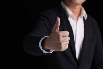 A confidence business man in black suit showing his thumb up.