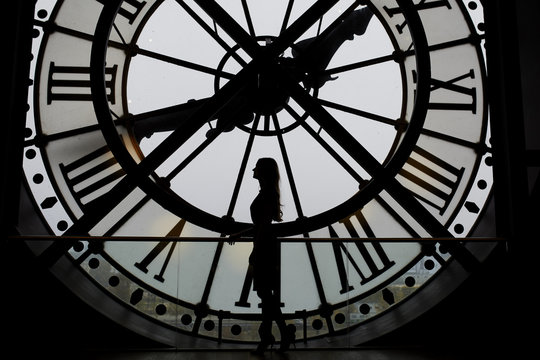 Woman silhouette standing in front of large clock