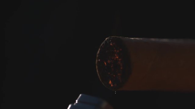 Slow-Mo ECU: Metal Lighter Igniting Cigarette. First Puff floating into frame.