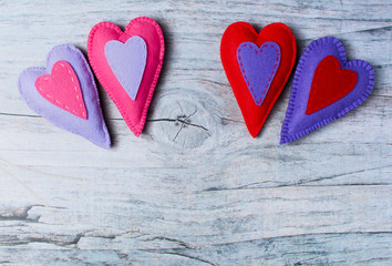 Hand made felt colorful hearts on wooden background