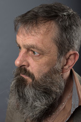 Photo of an angry grumpy old man looking very displeased. Male man with long beard on his face. Close up face looking into the camera.
