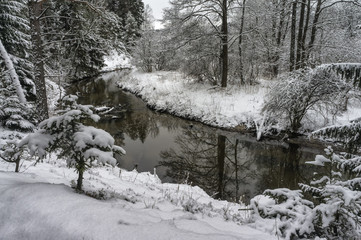 Small river in a snowy winter forest