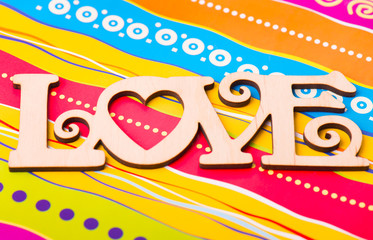 Wooden plaque "love" on a colorful background