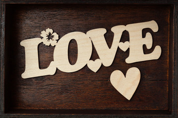 Inscription love and heart on a wooden background