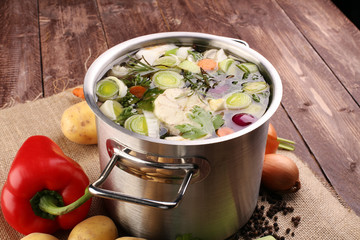 Broth with carrots, onions various fresh vegetables in a pot - c