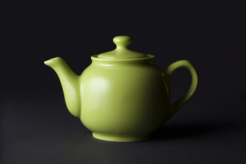 Matte green ceramic teapot isolated on black background