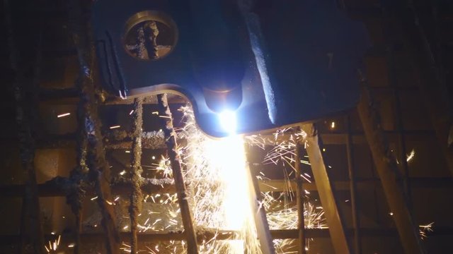 Welder cutting autogenous the metallic detail. Sparks flying down. Slow motion, high speed camera, 250fps