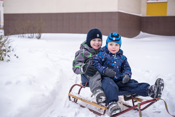 Fototapeta na wymiar Winter holidays fun. Two boys have together sliding on a pleasan