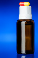 glass bottle cough syrup with a pill.